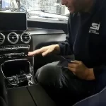 A mechanic inspecting the jammed center console in a 2018 Mercedes C300.