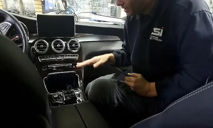 A mechanic inspecting the jammed center console in a 2018 Mercedes C300.